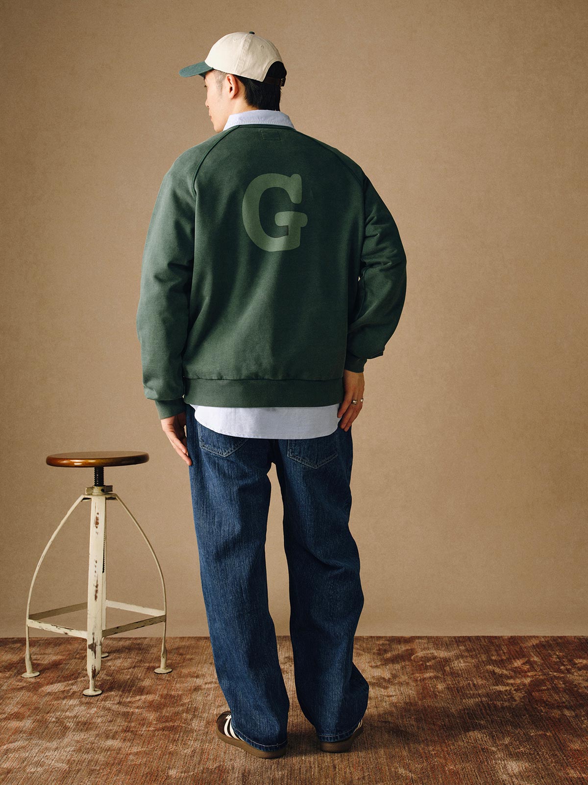 詳細画像
「胸元の英文字プリントとスノーウォッシュ加工による色落ち感が際立つ生地のディテールクローズアップ。柔らかな肌触りと褪色の質感が魅力。」
モデル画像
「モデルがピンクベージュの色落ち加工スウェットを着用し、カジュアルパンツと合わせたレトロでスポーティなヴィンテージ風コーディネート。」