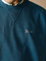 詳細画像
「胸元の英文字プリントとスノーウォッシュ加工による色落ち感が際立つ生地のディテールクローズアップ。柔らかな肌触りと褪色の質感が魅力。」
モデル画像
「モデルがピンクベージュの色落ち加工スウェットを着用し、カジュアルパンツと合わせたレトロでスポーティなヴィンテージ風コーディネート。」