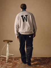 詳細画像
「胸元の英文字プリントとスノーウォッシュ加工による色落ち感が際立つ生地のディテールクローズアップ。柔らかな肌触りと褪色の質感が魅力。」
モデル画像
「モデルがピンクベージュの色落ち加工スウェットを着用し、カジュアルパンツと合わせたレトロでスポーティなヴィンテージ風コーディネート。」