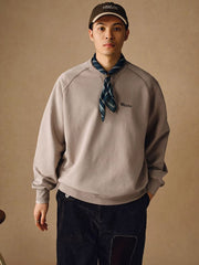 詳細画像
「胸元の英文字プリントとスノーウォッシュ加工による色落ち感が際立つ生地のディテールクローズアップ。柔らかな肌触りと褪色の質感が魅力。」
モデル画像
「モデルがピンクベージュの色落ち加工スウェットを着用し、カジュアルパンツと合わせたレトロでスポーティなヴィンテージ風コーディネート。」