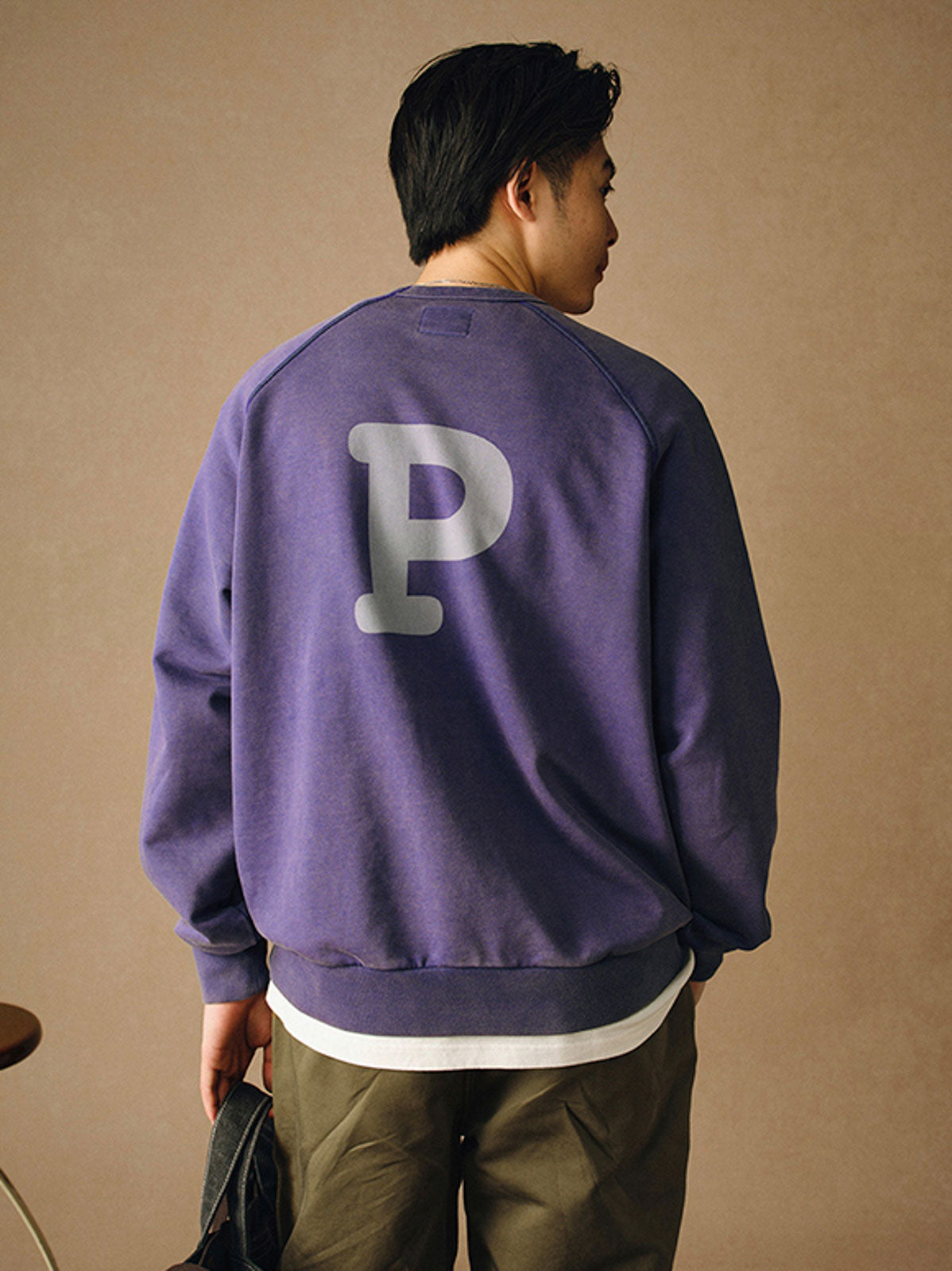 詳細画像
「胸元の英文字プリントとスノーウォッシュ加工による色落ち感が際立つ生地のディテールクローズアップ。柔らかな肌触りと褪色の質感が魅力。」
モデル画像
「モデルがピンクベージュの色落ち加工スウェットを着用し、カジュアルパンツと合わせたレトロでスポーティなヴィンテージ風コーディネート。」