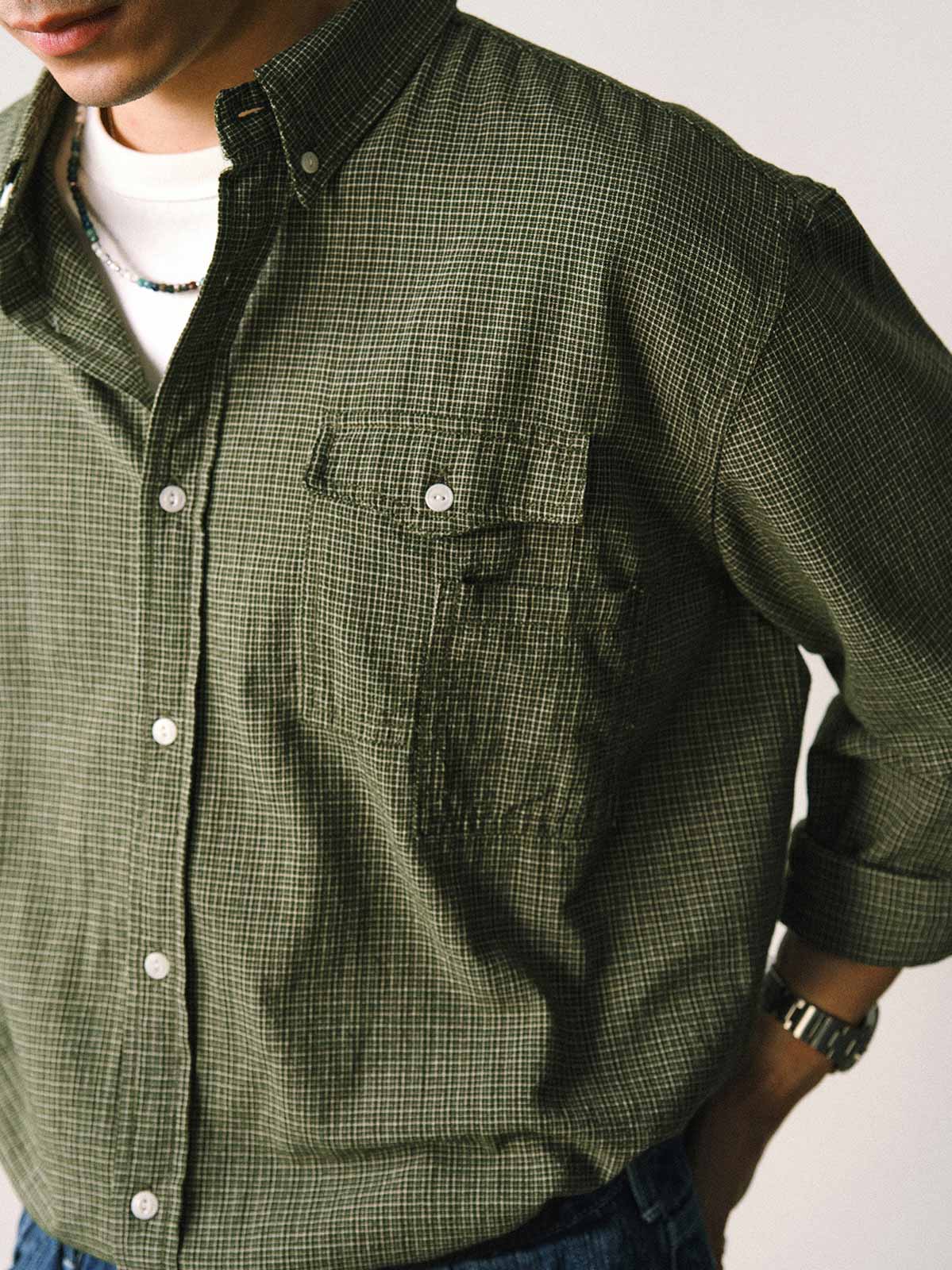 詳細画像
「胸元のユニークな配置のパッチポケットと立体感のあるチェック柄生地のディテールをクローズアップ。シワになりにくい特性も備えた高品質なコットン素材。」
モデル画像
「モデルがネイビーのチェック柄パッチポケットシャツを着用し、デニムパンツと合わせたカジュアルなコーディネートを披露。」