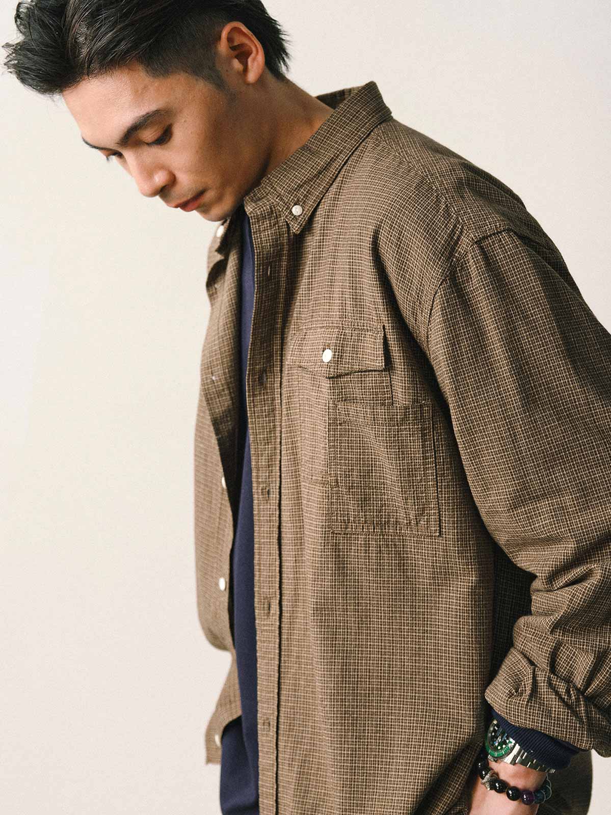 詳細画像
「胸元のユニークな配置のパッチポケットと立体感のあるチェック柄生地のディテールをクローズアップ。シワになりにくい特性も備えた高品質なコットン素材。」
モデル画像
「モデルがネイビーのチェック柄パッチポケットシャツを着用し、デニムパンツと合わせたカジュアルなコーディネートを披露。」