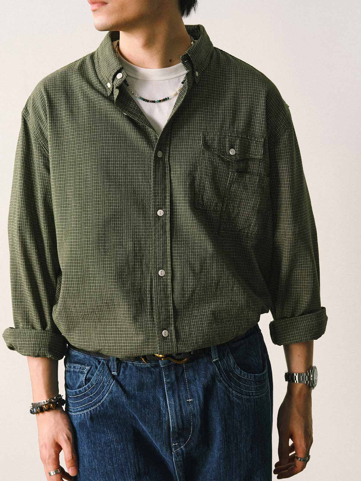 詳細画像
「胸元のユニークな配置のパッチポケットと立体感のあるチェック柄生地のディテールをクローズアップ。シワになりにくい特性も備えた高品質なコットン素材。」
モデル画像
「モデルがネイビーのチェック柄パッチポケットシャツを着用し、デニムパンツと合わせたカジュアルなコーディネートを披露。」