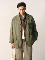 詳細画像
「バイカラーの胸ポケットやアシンメトリーな複合ポケットのディテールクローズアップ。酵素ウォッシュ加工による自然な色褪せ感と軽い起毛感が特徴。」
モデル画像
「モデルがアーミーグリーンのウォッシュ加工ワークテイストテーラードジャケットをデニムと合わせたヴィンテージ風カジュアルワークコーディネート。」