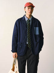 詳細画像
「バイカラーの胸ポケットやアシンメトリーな複合ポケットのディテールクローズアップ。酵素ウォッシュ加工による自然な色褪せ感と軽い起毛感が特徴。」
モデル画像
「モデルがアーミーグリーンのウォッシュ加工ワークテイストテーラードジャケットをデニムと合わせたヴィンテージ風カジュアルワークコーディネート。」