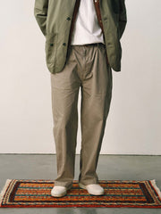 詳細画像
「スラブツイルの竹節模様とヘリンボーンパターンの切り替えデザインをクローズアップ。自然な色褪せ感とパイピング仕上げが高級感を引き立てるディテール。」
モデル画像
「モデルが白シャツとスニーカーを合わせて着用したカーキのヴィンテージ加工スラブ織りテクスチャーパンツのコーディネート。」