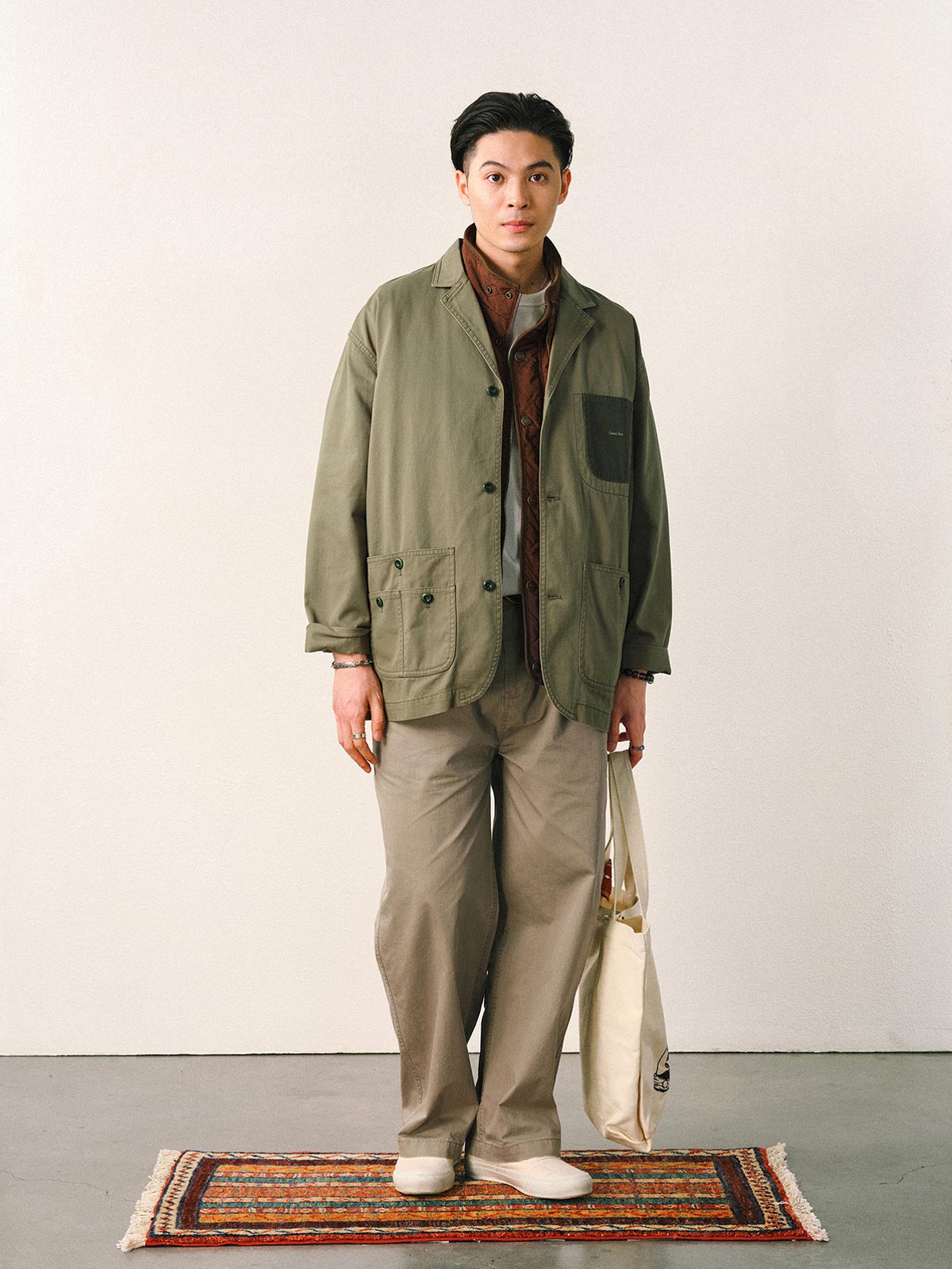 詳細画像
「スラブツイルの竹節模様とヘリンボーンパターンの切り替えデザインをクローズアップ。自然な色褪せ感とパイピング仕上げが高級感を引き立てるディテール。」
モデル画像
「モデルが白シャツとスニーカーを合わせて着用したカーキのヴィンテージ加工スラブ織りテクスチャーパンツのコーディネート。」