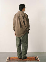 詳細画像
「スラブツイルの竹節模様とヘリンボーンパターンの切り替えデザインをクローズアップ。自然な色褪せ感とパイピング仕上げが高級感を引き立てるディテール。」
モデル画像
「モデルが白シャツとスニーカーを合わせて着用したカーキのヴィンテージ加工スラブ織りテクスチャーパンツのコーディネート。」