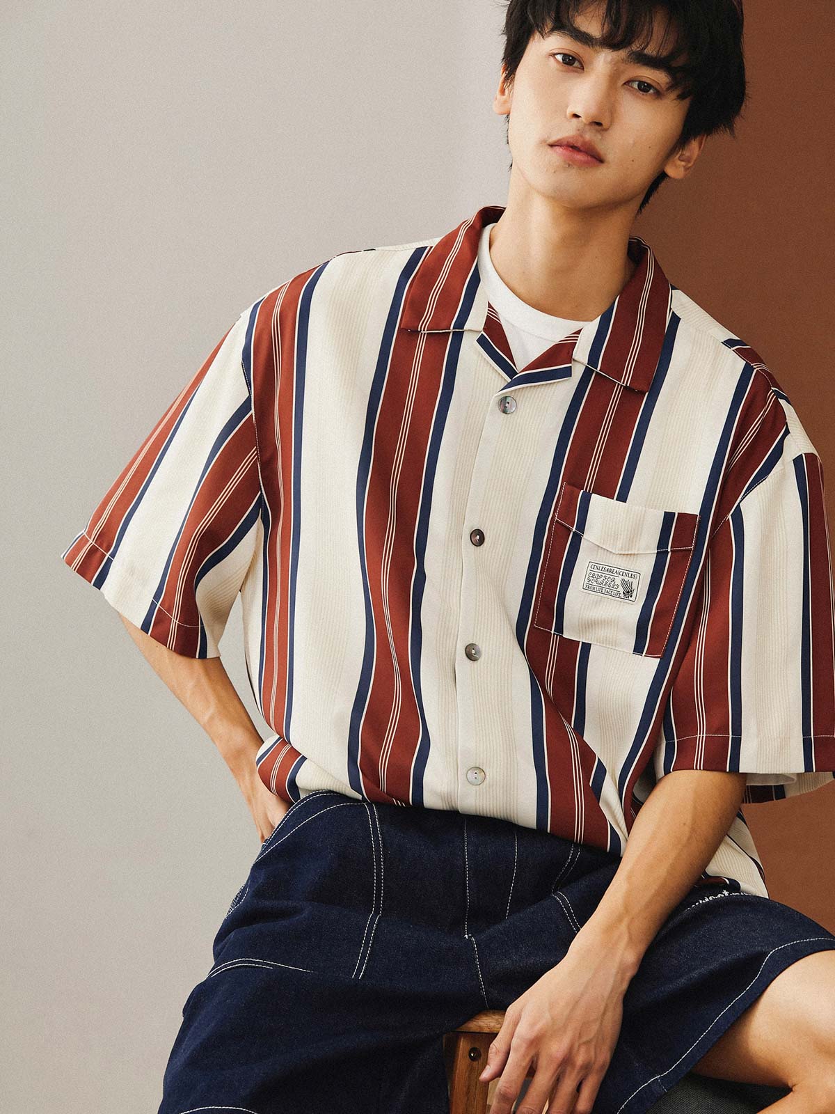 モデルがレトロスタイルのストライプハワイアン半袖シャツを着用し、ライトカラーのジーンズとカジュアルシューズでスタイリング。夏のカジュアルスタイルやビーチリゾートに最適な組み合わせを提案しています。