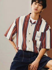 モデルがレトロスタイルのストライプハワイアン半袖シャツを着用し、ライトカラーのジーンズとカジュアルシューズでスタイリング。夏のカジュアルスタイルやビーチリゾートに最適な組み合わせを提案しています。