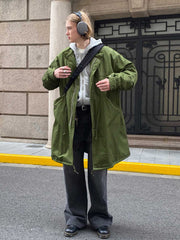 詳細画像: M-65改良型 厚手パーカーコート(ロング)のディテールクローズアップ画像。ウエストライン調整が可能なドローコードと、鍵やスマートフォンなどの収納に便利な多機能ポケットのデザインが映える。防風性を考慮した耐久性の高いコットン素材の質感が際立つ。
モデル画像: モデルが着用した**M-65改良型 厚手パーカーコート(ロング)**の全身コーディネートイメージ。ゆったりとしたシルエットとクラシックなミリタリースタイルを合わせ、ブーツやカジュアルシューズと相性抜群。アウトドアから日常使いまで幅広いシーンに対応する冬のスタイリング例。