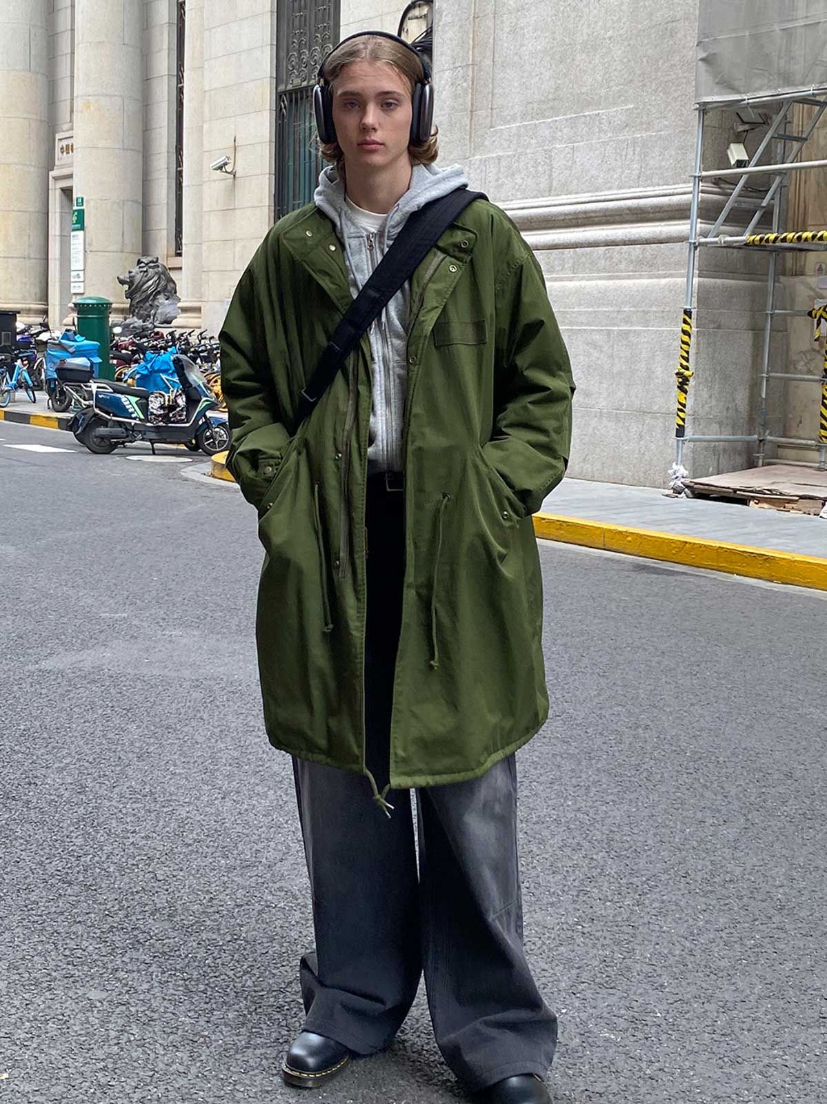 詳細画像: M-65改良型 厚手パーカーコート(ロング)のディテールクローズアップ画像。ウエストライン調整が可能なドローコードと、鍵やスマートフォンなどの収納に便利な多機能ポケットのデザインが映える。防風性を考慮した耐久性の高いコットン素材の質感が際立つ。
モデル画像: モデルが着用した**M-65改良型 厚手パーカーコート(ロング)**の全身コーディネートイメージ。ゆったりとしたシルエットとクラシックなミリタリースタイルを合わせ、ブーツやカジュアルシューズと相性抜群。アウトドアから日常使いまで幅広いシーンに対応する冬のスタイリング例。