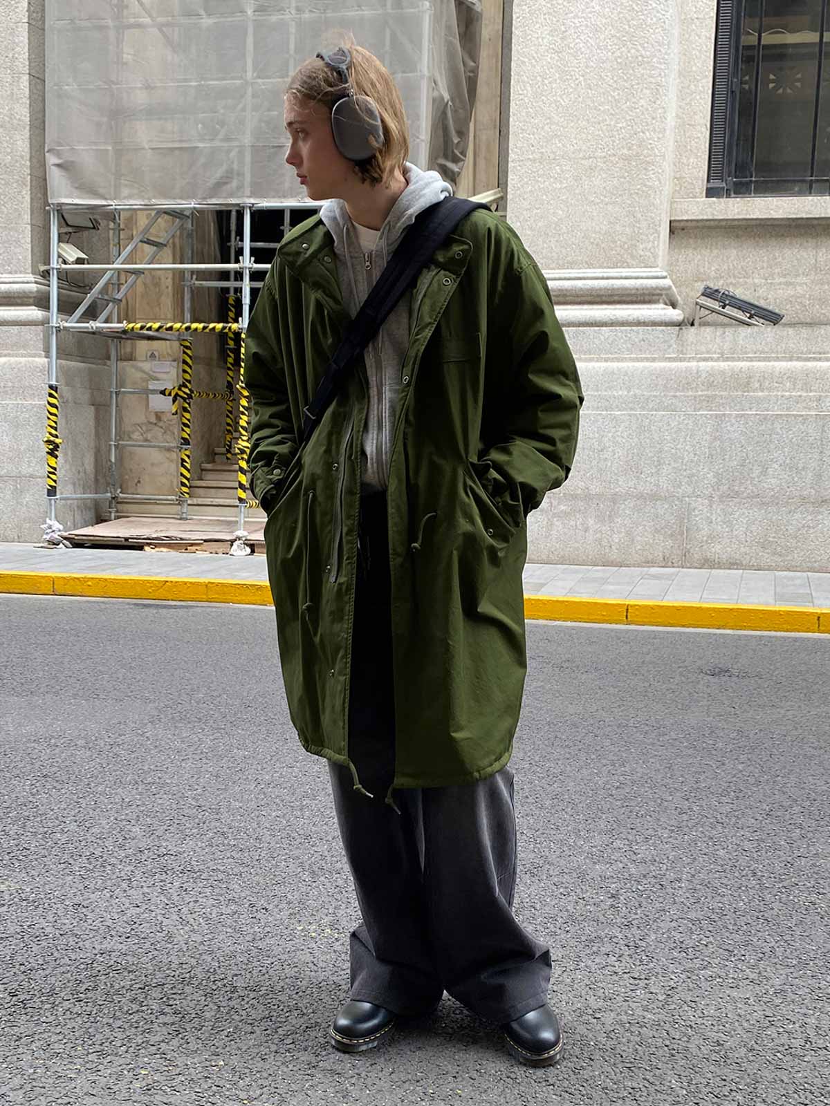 詳細画像: M-65改良型 厚手パーカーコート(ロング)のディテールクローズアップ画像。ウエストライン調整が可能なドローコードと、鍵やスマートフォンなどの収納に便利な多機能ポケットのデザインが映える。防風性を考慮した耐久性の高いコットン素材の質感が際立つ。
モデル画像: モデルが着用した**M-65改良型 厚手パーカーコート(ロング)**の全身コーディネートイメージ。ゆったりとしたシルエットとクラシックなミリタリースタイルを合わせ、ブーツやカジュアルシューズと相性抜群。アウトドアから日常使いまで幅広いシーンに対応する冬のスタイリング例。