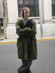 詳細画像: M-65改良型 厚手パーカーコート(ロング)のディテールクローズアップ画像。ウエストライン調整が可能なドローコードと、鍵やスマートフォンなどの収納に便利な多機能ポケットのデザインが映える。防風性を考慮した耐久性の高いコットン素材の質感が際立つ。
モデル画像: モデルが着用した**M-65改良型 厚手パーカーコート(ロング)**の全身コーディネートイメージ。ゆったりとしたシルエットとクラシックなミリタリースタイルを合わせ、ブーツやカジュアルシューズと相性抜群。アウトドアから日常使いまで幅広いシーンに対応する冬のスタイリング例。