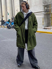 詳細画像: M-65改良型 厚手パーカーコート(ロング)のディテールクローズアップ画像。ウエストライン調整が可能なドローコードと、鍵やスマートフォンなどの収納に便利な多機能ポケットのデザインが映える。防風性を考慮した耐久性の高いコットン素材の質感が際立つ。
モデル画像: モデルが着用した**M-65改良型 厚手パーカーコート(ロング)**の全身コーディネートイメージ。ゆったりとしたシルエットとクラシックなミリタリースタイルを合わせ、ブーツやカジュアルシューズと相性抜群。アウトドアから日常使いまで幅広いシーンに対応する冬のスタイリング例。