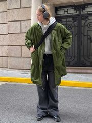 詳細画像: M-65改良型 厚手パーカーコート(ロング)のディテールクローズアップ画像。ウエストライン調整が可能なドローコードと、鍵やスマートフォンなどの収納に便利な多機能ポケットのデザインが映える。防風性を考慮した耐久性の高いコットン素材の質感が際立つ。
モデル画像: モデルが着用した**M-65改良型 厚手パーカーコート(ロング)**の全身コーディネートイメージ。ゆったりとしたシルエットとクラシックなミリタリースタイルを合わせ、ブーツやカジュアルシューズと相性抜群。アウトドアから日常使いまで幅広いシーンに対応する冬のスタイリング例。