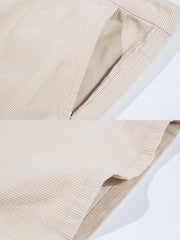 製品画像: 14ウェールのコットンコーデュロイ素材を使用したワイドパンツの全体画像。柔らかな肌触りと自然なドレープ感が魅力的で、通勤やカジュアルシーンにぴったりの一着。
詳細画像: コーデュロイ素材のディテールと裾デザインを映したクローズアップ画像。製品染め加工による深みのあるカラーと、ワイドシルエットの滑らかなラインが際立つ。