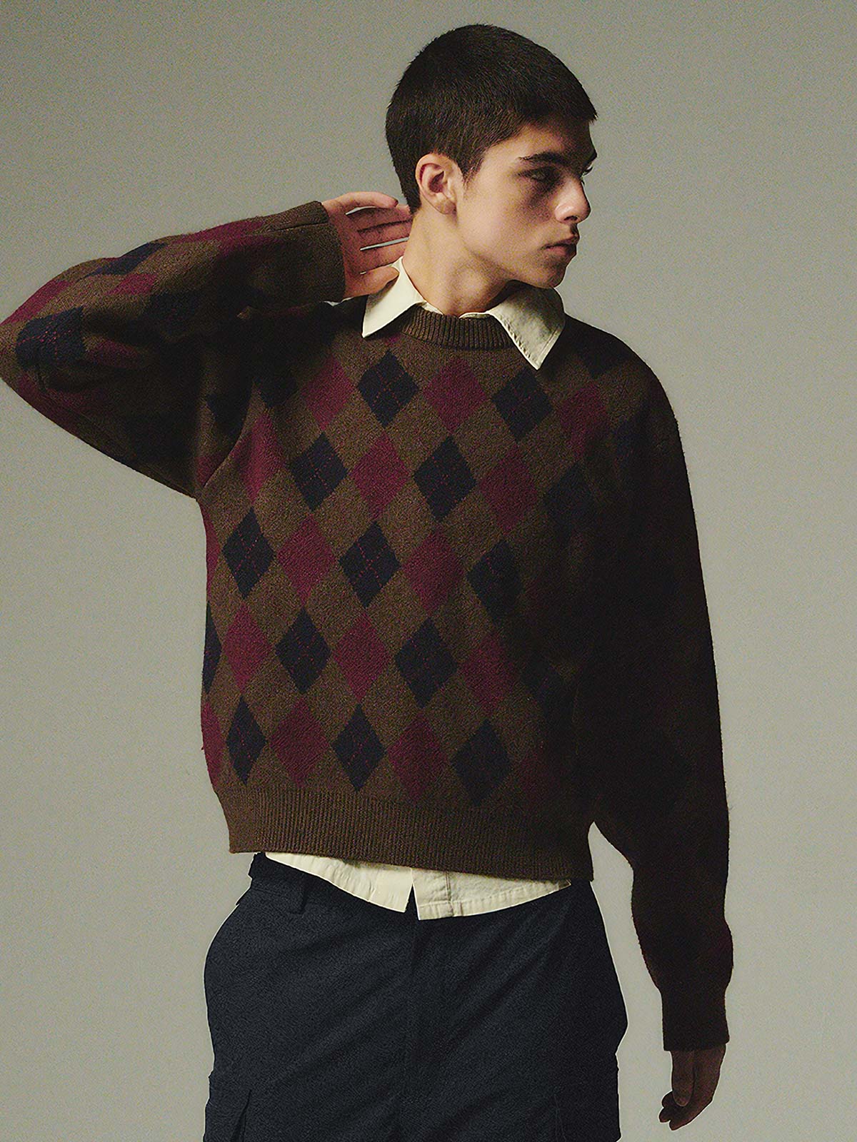 詳細画像: ダイヤ柄の滑らかな編み地のディテールクローズアップ画像。軽量で柔らかい混紡素材が持つ快適さと暖かさを示す。
モデル画像: ダイヤ柄クルーネックニットを着用したモデルによるカジュアルコーディネートイメージ。デニムやワークパンツとの組み合わせでレトロなスタイルを楽しめる。