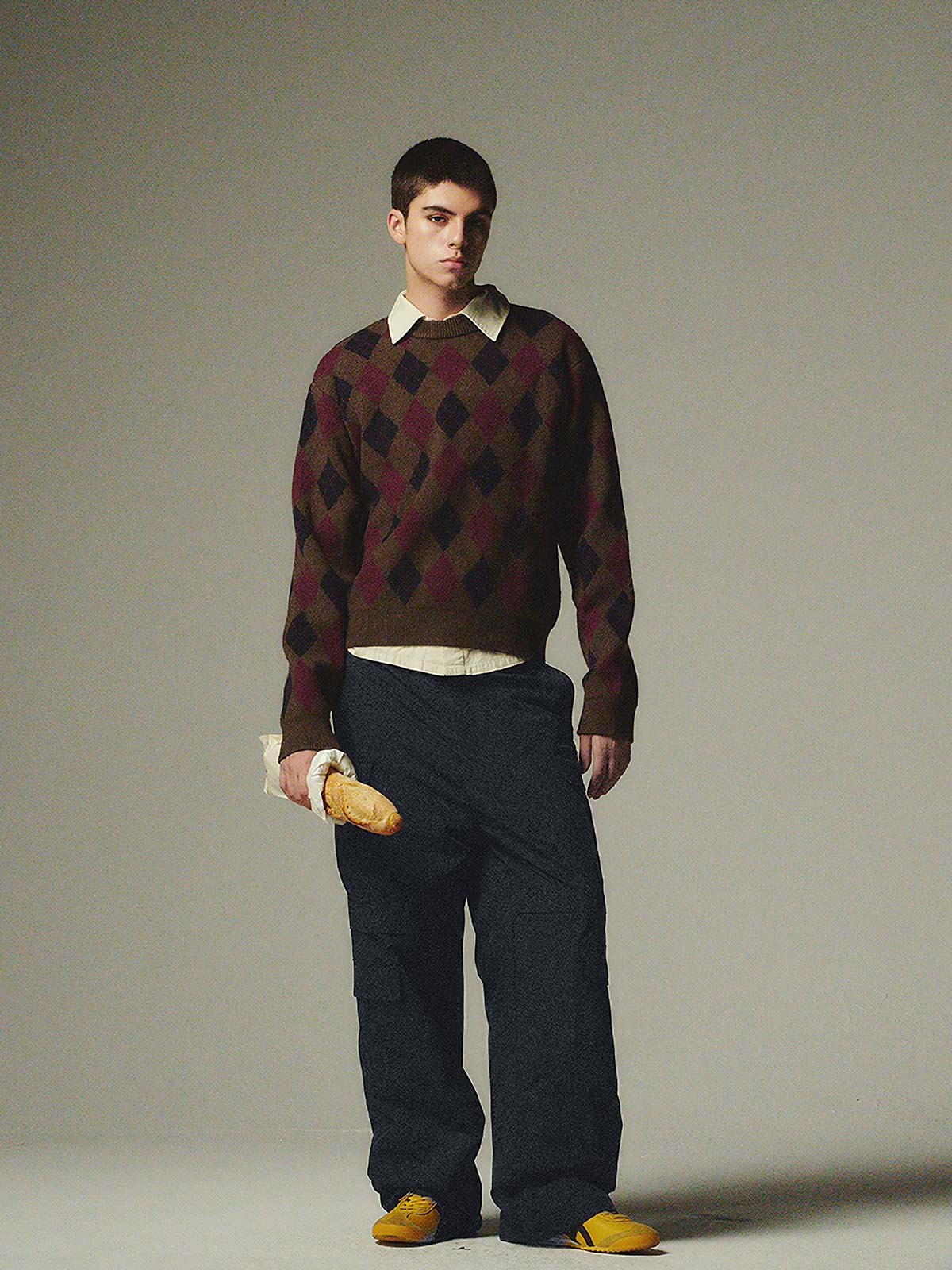 詳細画像: ダイヤ柄の滑らかな編み地のディテールクローズアップ画像。軽量で柔らかい混紡素材が持つ快適さと暖かさを示す。
モデル画像: ダイヤ柄クルーネックニットを着用したモデルによるカジュアルコーディネートイメージ。デニムやワークパンツとの組み合わせでレトロなスタイルを楽しめる。