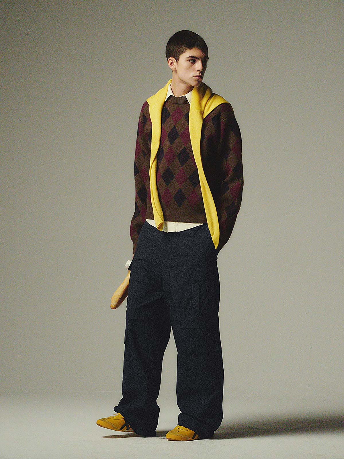 詳細画像: ダイヤ柄の滑らかな編み地のディテールクローズアップ画像。軽量で柔らかい混紡素材が持つ快適さと暖かさを示す。
モデル画像: ダイヤ柄クルーネックニットを着用したモデルによるカジュアルコーディネートイメージ。デニムやワークパンツとの組み合わせでレトロなスタイルを楽しめる。