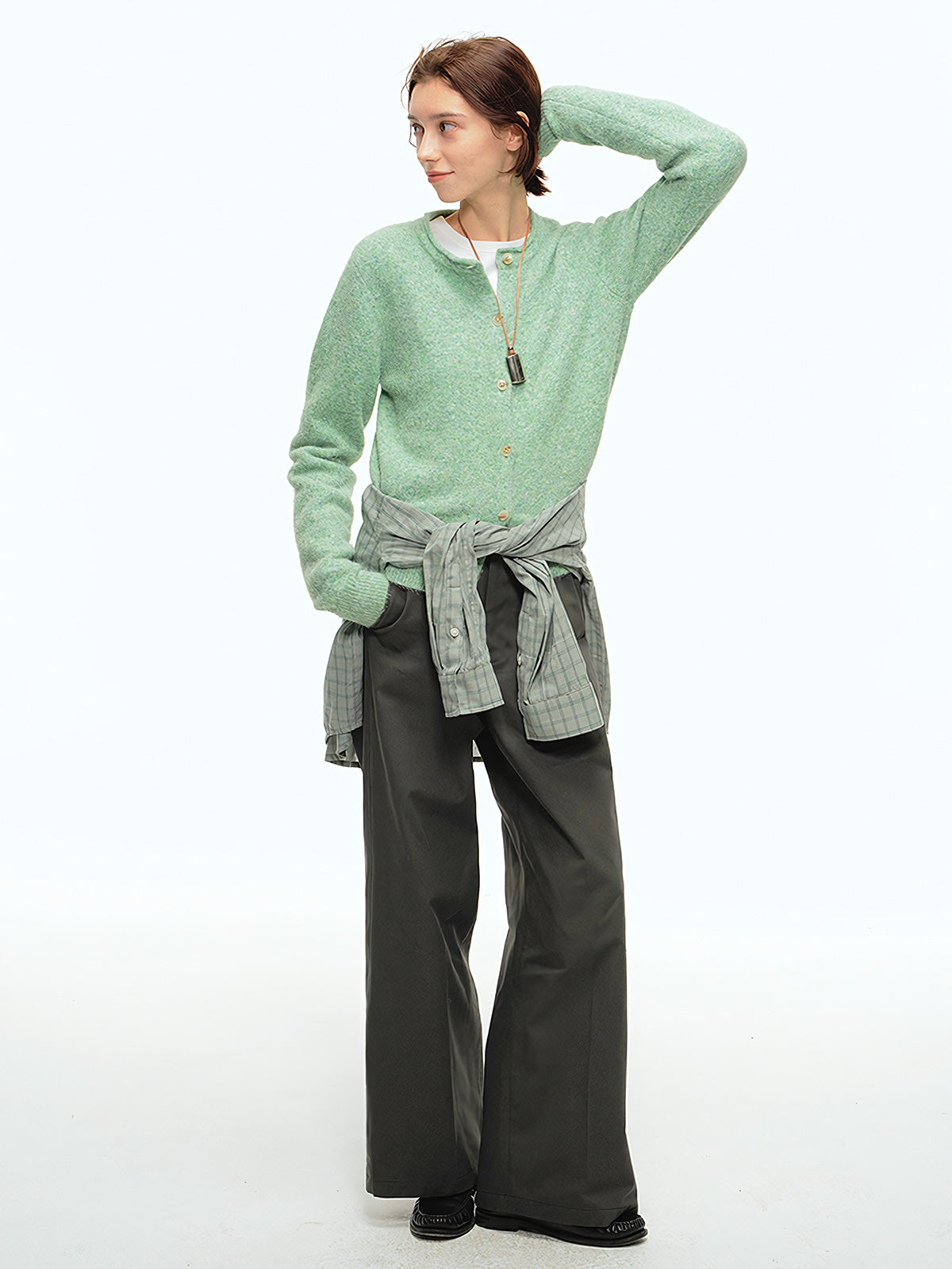 詳細画像: 前中プリーツデザインとハイウエストディテールのクローズアップ、優雅なドレープ感と流れるようなラインを強調
モデル画像: ワイドレッグスラックスをシンプルなシャツと合わせた通勤スタイル、ヴィンテージ感あふれるミニマルなコーディネート