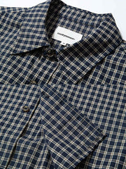 製品画像: クラシックなチェック柄デザインとショート丈シルエットが特徴の長袖シャツ全体展示、100%コットン素材使用、シンプルでモダンなスタイル
詳細画像: チェック柄と胸部ポケットのユニークなディテール特写、柔らかな肌触りと通気性を強調したコットン素材