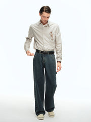 詳細画像: ブルーの細ストライプと胸元のポケットディテール特写、ヴィンテージカットが強調された部分
モデル画像: モデルが100%コットンストライプシャツを着用し、シンプルでヴィンテージ感のあるカジュアルスタイルを披露