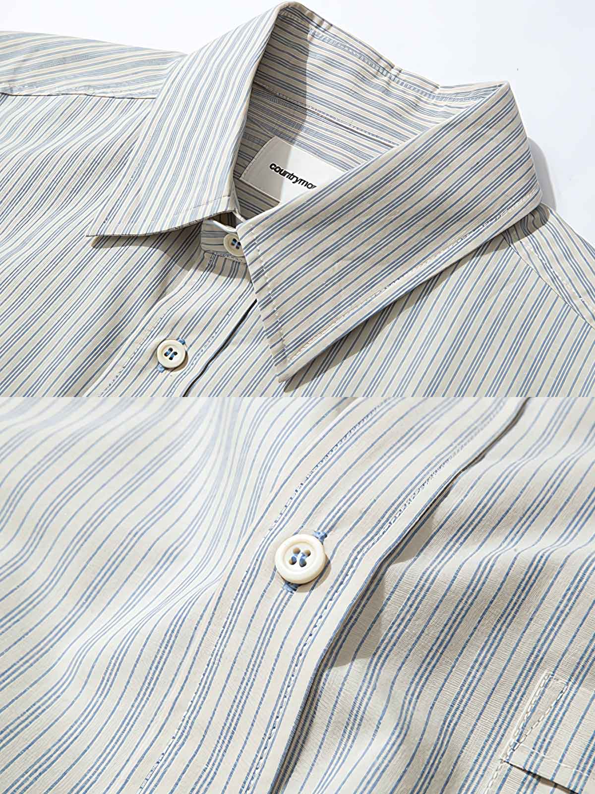 製品画像: クラシックなブルーの細ストライプデザインを採用した100%コットン製の長袖シャツ全体展示、シンプルで万能なレトロなスタイル
詳細画像: ブルーの細ストライプと胸元のポケットディテール特写、ヴィンテージカットが強調された部分