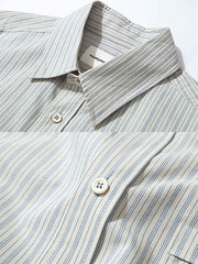 製品画像: クラシックなブルーの細ストライプデザインを採用した100%コットン製の長袖シャツ全体展示、シンプルで万能なレトロなスタイル
詳細画像: ブルーの細ストライプと胸元のポケットディテール特写、ヴィンテージカットが強調された部分