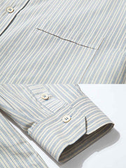 製品画像: クラシックなブルーの細ストライプデザインを採用した100%コットン製の長袖シャツ全体展示、シンプルで万能なレトロなスタイル
詳細画像: ブルーの細ストライプと胸元のポケットディテール特写、ヴィンテージカットが強調された部分