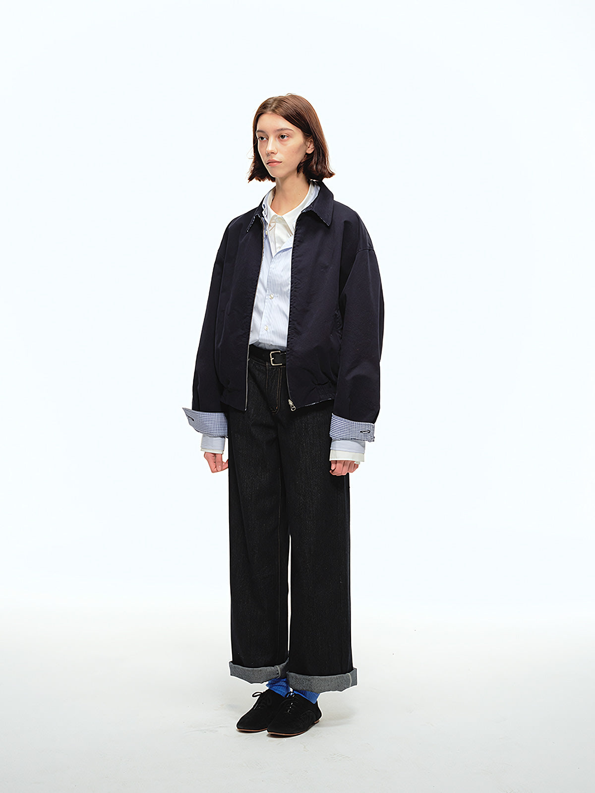 詳細画像: 袖口のバイカラー折り返しデザインとリバーシブルデザインのディテール、ヴィンテージチェック柄と単色面が交互に見える部分のクローズアップ
モデル画像: モデルがリバーシブルハリントンジャケットを使ったヴィンテージ感とモダンなコーディネート、カジュアルなスタイルを披露