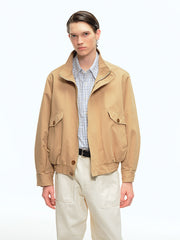 詳細画像: ドレーピングカットによる立体感、スタンドカラーのディテール、大容量ポケットのクローズアップ
モデル画像: ドレーピングスタンドカラーのワークジャケットをカジュアルパンツと合わせたスタイリッシュなコーディネート、アウトドアや日常の着用に最適なスタイル