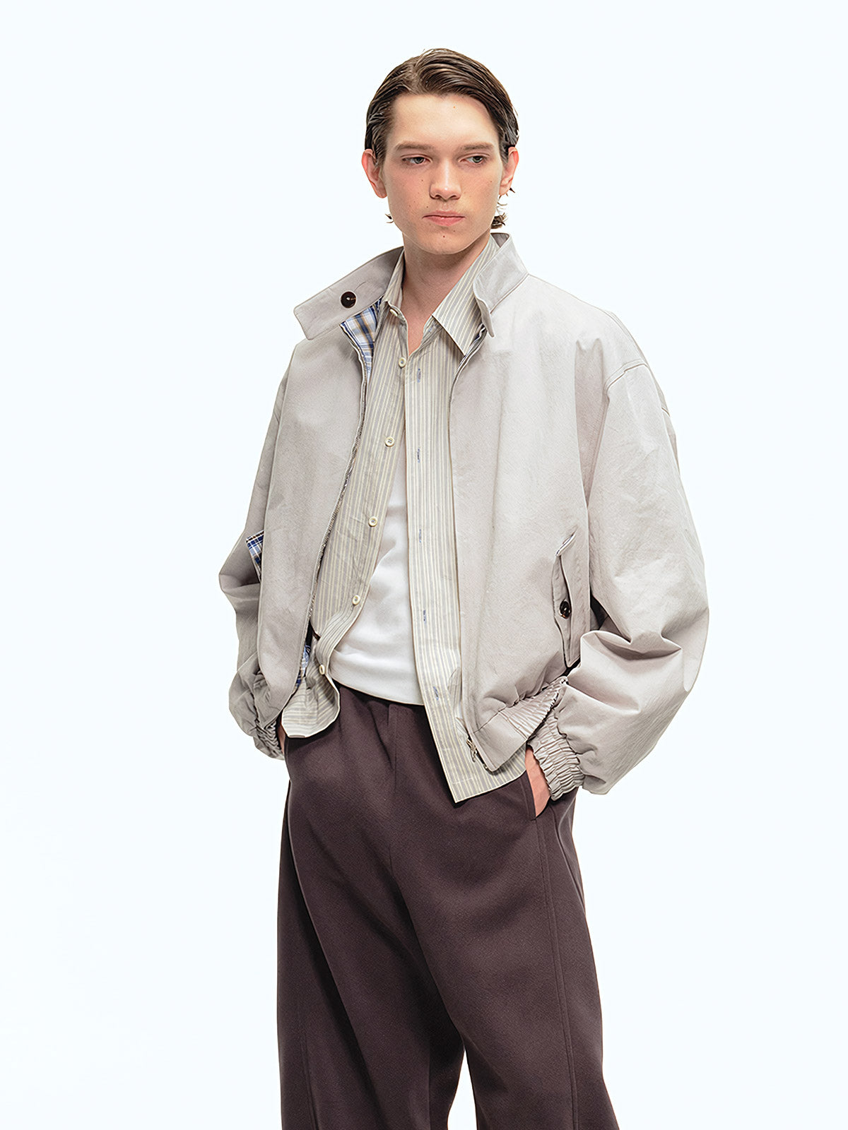 詳細画像: このジャケットの詳細な画像には、チェック柄と無地のリバーシブルデザインがしっかりと反映されており、スタンドカラーのディテール、ジッパー付きのデザイン、リブ袖口と風防デザインが見事に融合して、機能性とデザイン性を兼ね備えた仕上がりとなっています。また、内側のチェック柄ディテールも鮮明に見えるクローズアップで、品質感を際立たせています。
モデル画像: モデル画像では、このリバーシブルハリントンジャケットがカジュアルジーンズと合わせて着用され、レトロスタイルが強調されており、快適でエレガントなコーディネートが演出されています。ジャケットの多機能性とファッション性が一目でわかるスタイルです。