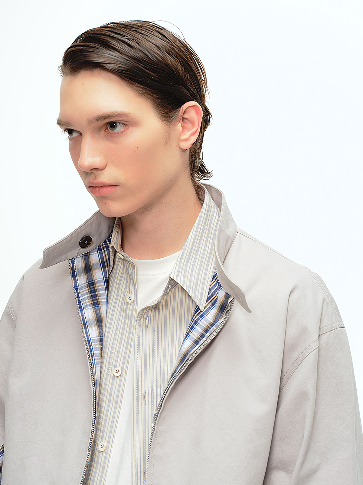 詳細画像: このジャケットの詳細な画像には、チェック柄と無地のリバーシブルデザインがしっかりと反映されており、スタンドカラーのディテール、ジッパー付きのデザイン、リブ袖口と風防デザインが見事に融合して、機能性とデザイン性を兼ね備えた仕上がりとなっています。また、内側のチェック柄ディテールも鮮明に見えるクローズアップで、品質感を際立たせています。
モデル画像: モデル画像では、このリバーシブルハリントンジャケットがカジュアルジーンズと合わせて着用され、レトロスタイルが強調されており、快適でエレガントなコーディネートが演出されています。ジャケットの多機能性とファッション性が一目でわかるスタイルです。