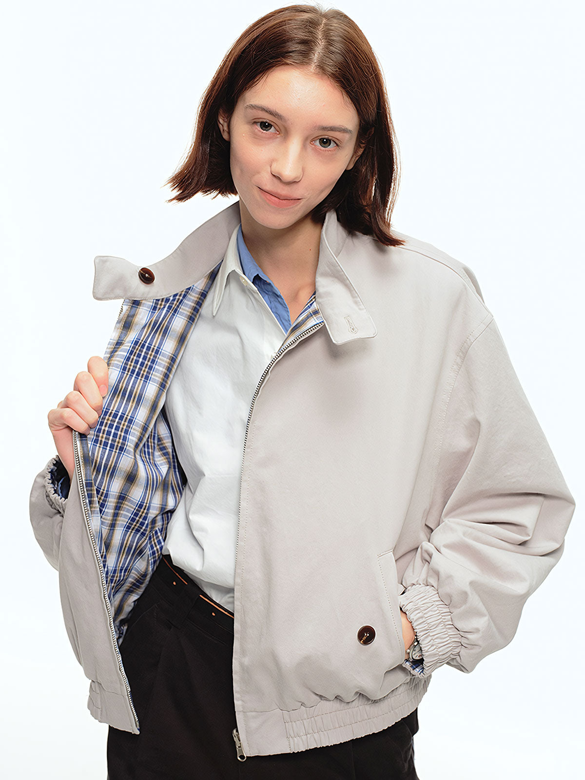 詳細画像: このジャケットの詳細な画像には、チェック柄と無地のリバーシブルデザインがしっかりと反映されており、スタンドカラーのディテール、ジッパー付きのデザイン、リブ袖口と風防デザインが見事に融合して、機能性とデザイン性を兼ね備えた仕上がりとなっています。また、内側のチェック柄ディテールも鮮明に見えるクローズアップで、品質感を際立たせています。
モデル画像: モデル画像では、このリバーシブルハリントンジャケットがカジュアルジーンズと合わせて着用され、レトロスタイルが強調されており、快適でエレガントなコーディネートが演出されています。ジャケットの多機能性とファッション性が一目でわかるスタイルです。