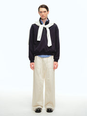 詳細画像: スタンドカラーとレザーパイピングのディテール特写。エコレザーの質感とハーフジップのディテールが強調され、デザイン性と実用性を高めています。
モデル画像: ハーフジップスウェットとカジュアルパンツを合わせたレトロで快適なスタイル。Boxyシルエットがリラックス感を与え、日常使いに最適なスタイリングを披露しています。