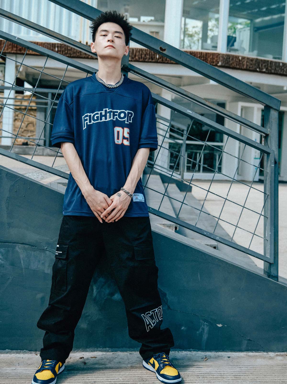 モデルが特別行動グループ ラグビーフットボールTシャツを着用し、ジーンズとシンプルなスニーカーで合わせたリラックスしたストリートスタイルを展示。カジュアルでアクティブな印象。