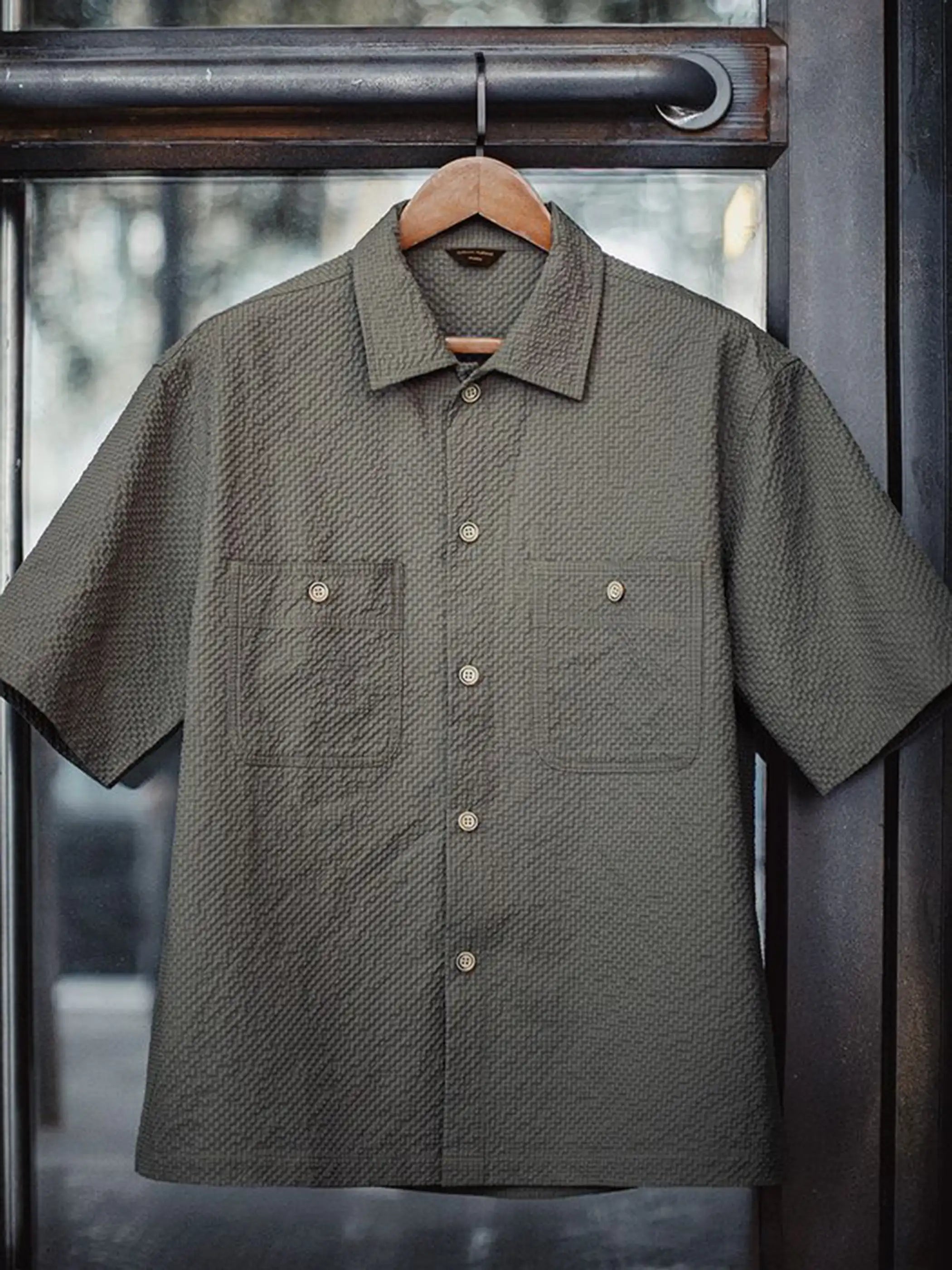 グレーのシアサッカー生地で仕立てられたワークシャツ、2つのフラップポケットがフロントに並ぶ