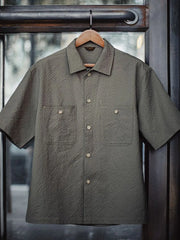 グレーのシアサッカー生地で仕立てられたワークシャツ、2つのフラップポケットがフロントに並ぶ