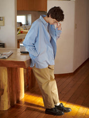 詳細画像: 胸ポケットとストライプ柄のディテール特写。精緻な織り目と均一なデザインが、ヴィンテージ感を引き立てつつ、現代的なカジュアルさも加えています。クロスステッチでの仕上げが、デザインの深みと耐久性を強調。
モデル画像: レトロストライプシャツとルーズパンツを合わせたカジュアルヴィンテージスタイル。ドロップショルダーとやや短めの丈が、現代的なカジュアル感を加え、快適で動きやすいシルエットを演出します。