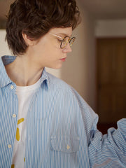 詳細画像: 胸ポケットとストライプ柄のディテール特写。精緻な織り目と均一なデザインが、ヴィンテージ感を引き立てつつ、現代的なカジュアルさも加えています。クロスステッチでの仕上げが、デザインの深みと耐久性を強調。
モデル画像: レトロストライプシャツとルーズパンツを合わせたカジュアルヴィンテージスタイル。ドロップショルダーとやや短めの丈が、現代的なカジュアル感を加え、快適で動きやすいシルエットを演出します。