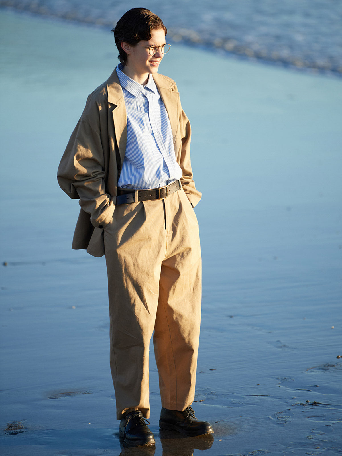 詳細画像: 胸ポケットとストライプ柄のディテール特写。精緻な織り目と均一なデザインが、ヴィンテージ感を引き立てつつ、現代的なカジュアルさも加えています。クロスステッチでの仕上げが、デザインの深みと耐久性を強調。
モデル画像: レトロストライプシャツとルーズパンツを合わせたカジュアルヴィンテージスタイル。ドロップショルダーとやや短めの丈が、現代的なカジュアル感を加え、快適で動きやすいシルエットを演出します。