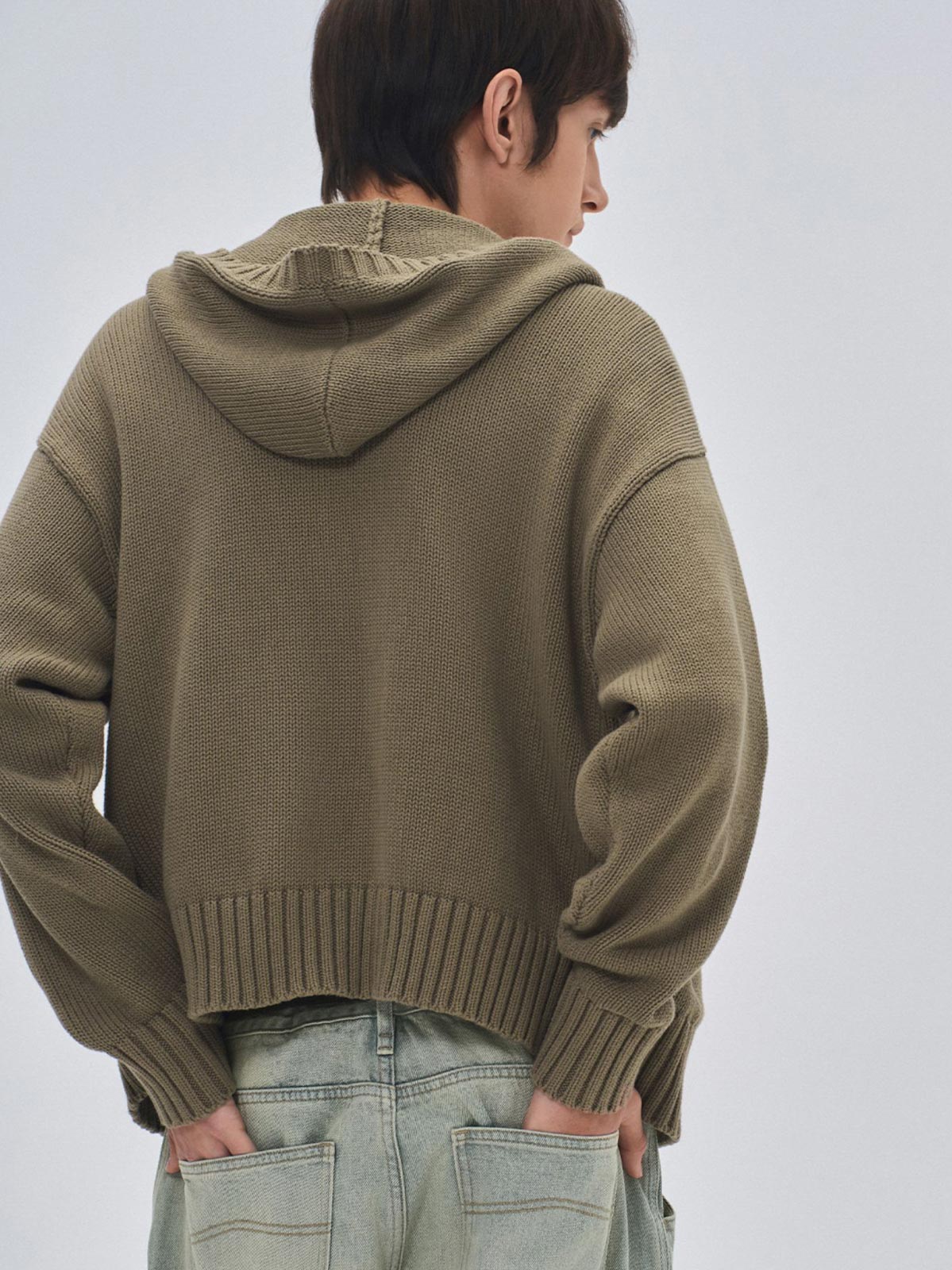 詳細画像: ケーブル編みディテールとマットシルバージッパーの特写。細部の編み模様とジッパーが際立つ画像。
モデル画像: ケーブル編みカーディガンとデニムを組み合わせた秋冬カジュアルスタイル。モデルがリラックスした日常スタイルを披露。