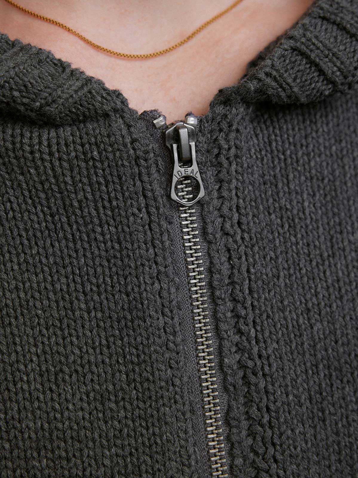 詳細画像: ケーブル編みディテールとマットシルバージッパーの特写。細部の編み模様とジッパーが際立つ画像。
モデル画像: ケーブル編みカーディガンとデニムを組み合わせた秋冬カジュアルスタイル。モデルがリラックスした日常スタイルを披露。