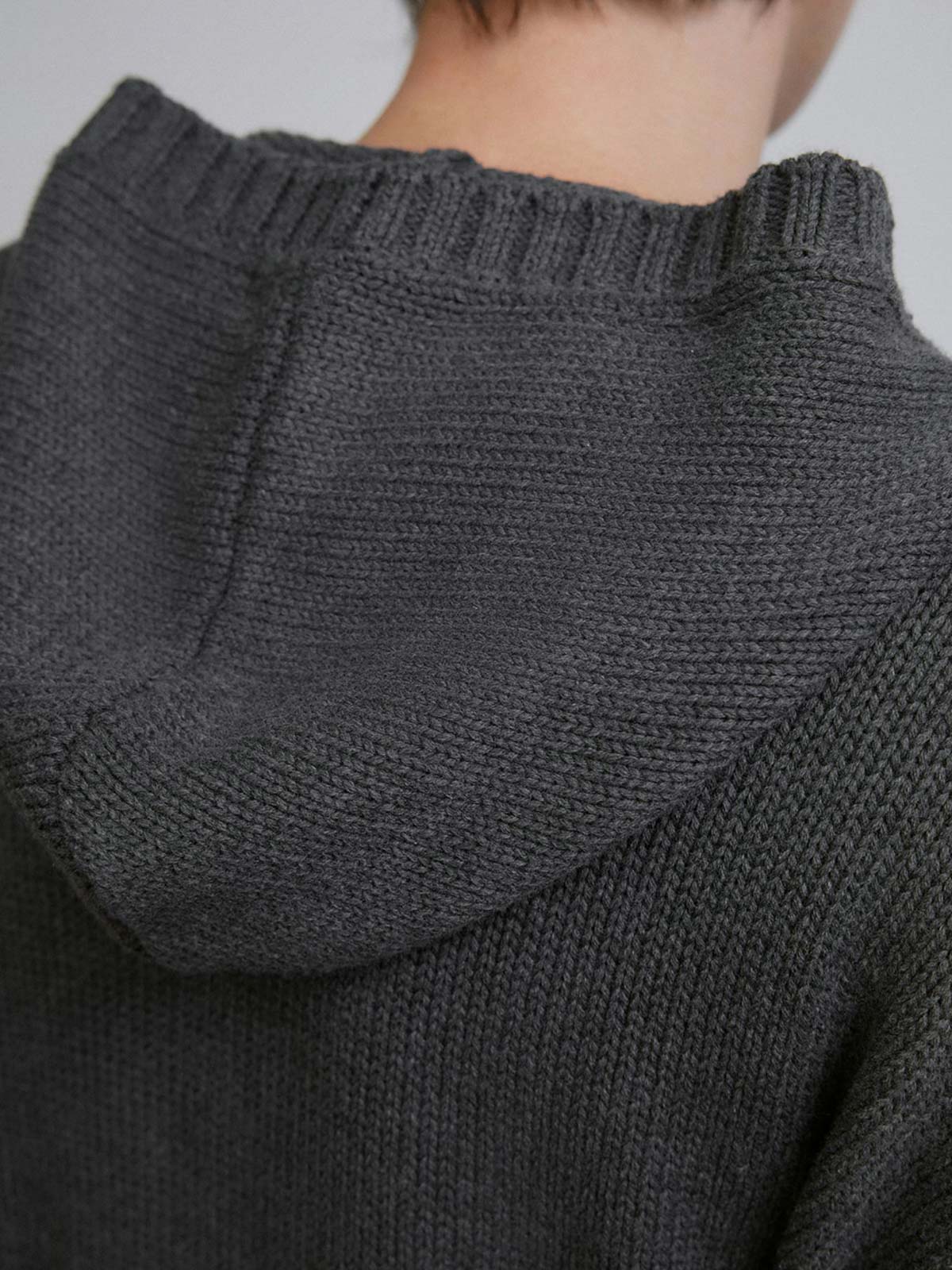 詳細画像: ケーブル編みディテールとマットシルバージッパーの特写。細部の編み模様とジッパーが際立つ画像。
モデル画像: ケーブル編みカーディガンとデニムを組み合わせた秋冬カジュアルスタイル。モデルがリラックスした日常スタイルを披露。