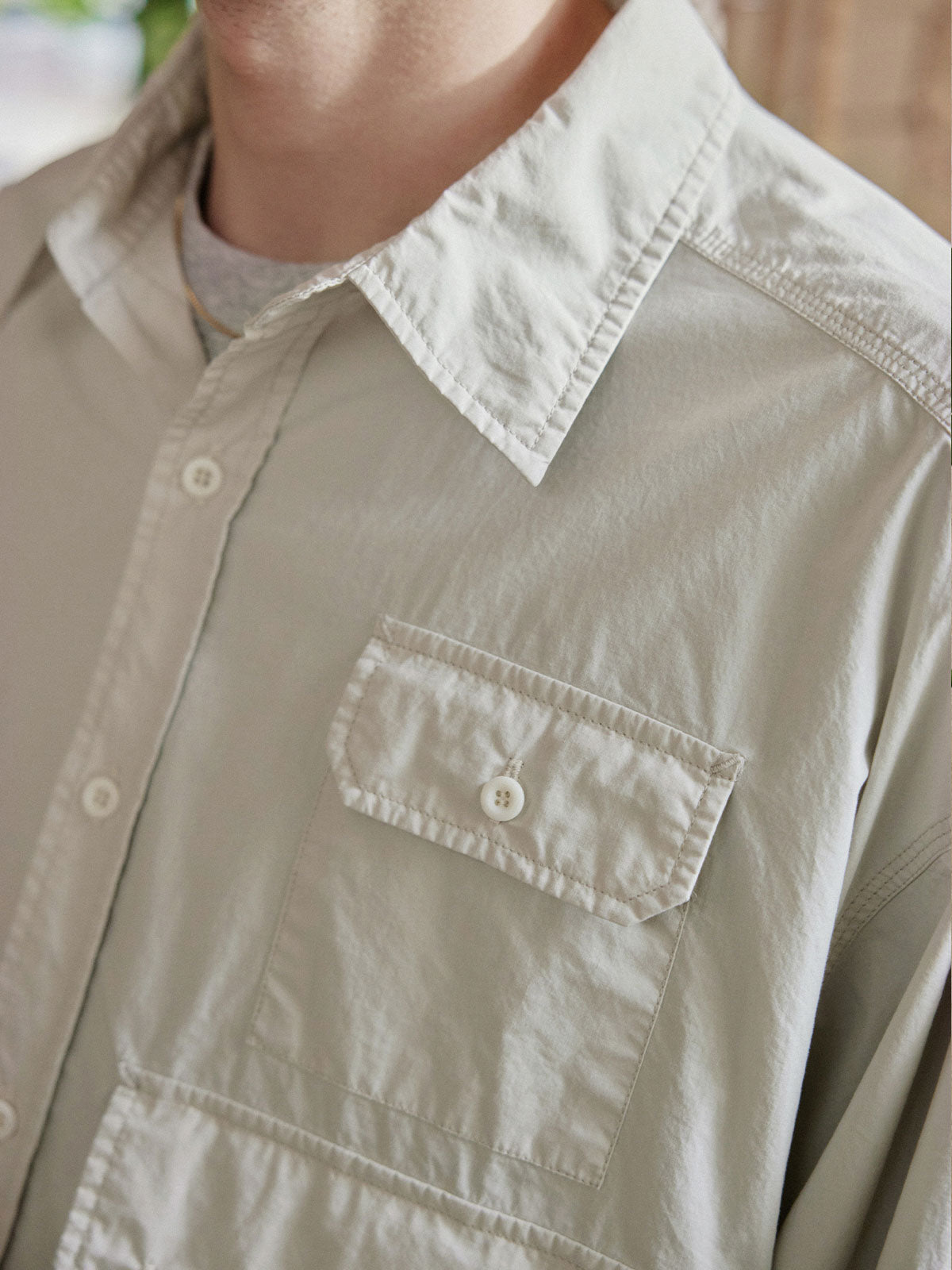 詳細画像: 胸元の3ポケットと酵素洗い加工ディテールの特写。ヴィンテージ感を引き立てるデザインで、機能性とファッション性を兼ね備えた仕上がり。
モデル画像: ワークシャツとアウトドアアイテムを組み合わせたレトロなアウトドアスタイルを披露するモデル。ジーンズやカーゴパンツとの相性も抜群。