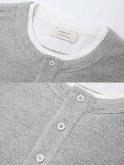 製品画像: ヘンリーネック レイヤード風 ワッフル 長袖Tシャツ全体展示。ヘンリーネックとレイヤード風デザインが融合したスタイル、ワッフル生地が独特の質感を引き立て、洗練されたカジュアル感を演出。
詳細画像: ワッフル生地のテクスチャーとレイヤードデザインの特写。独自の質感とディテールが着こなしに深みを加え、シンプルでありながらもデザイン性が光る。