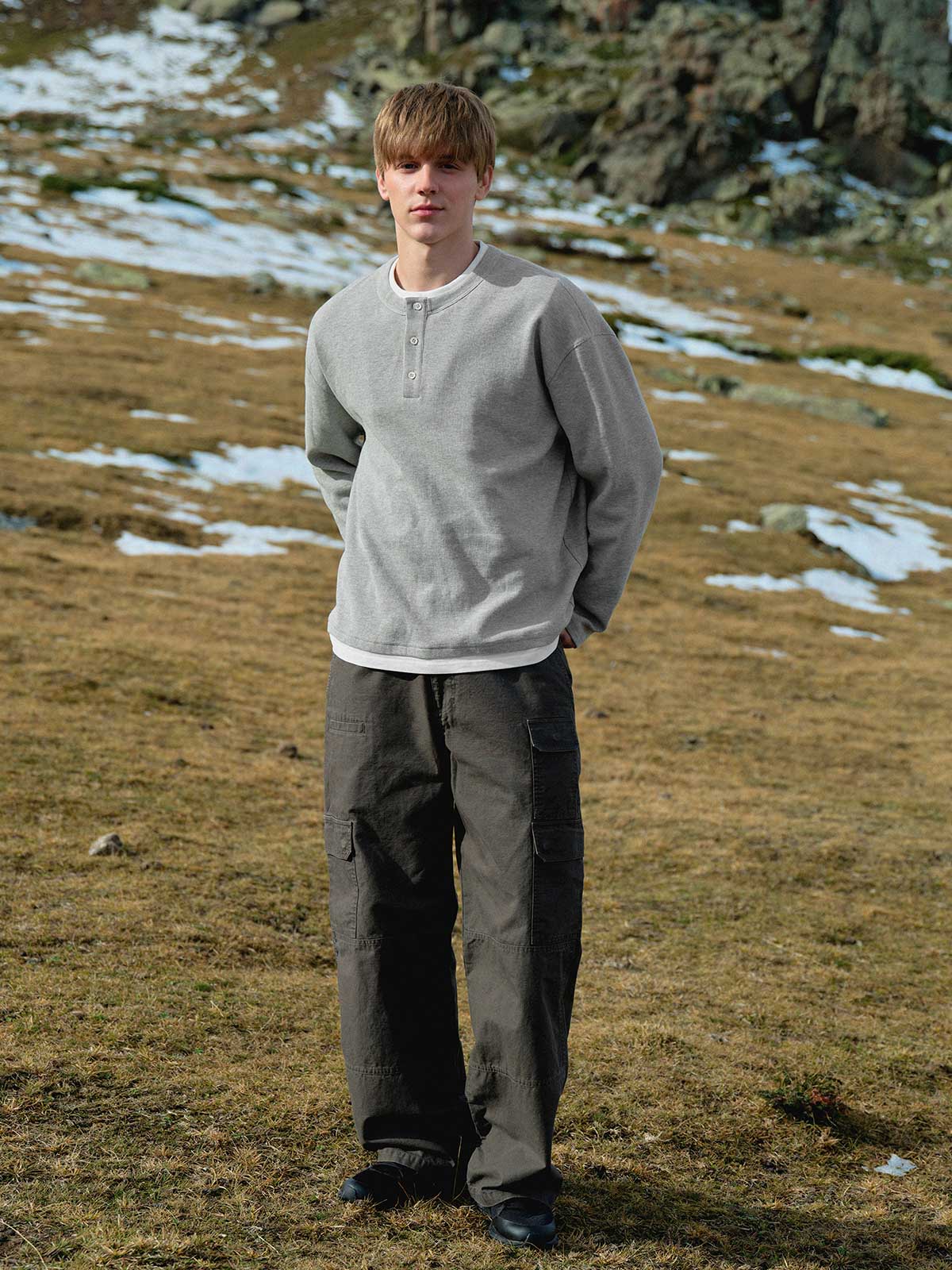 詳細画像: ワッフル生地のテクスチャーとレイヤードデザインの特写。独自の質感とディテールが着こなしに深みを加え、シンプルでありながらもデザイン性が光る。
モデル画像: ヘンリーネック長袖Tシャツを着用したカジュアルなレイヤードスタイルを披露するモデル。ゆったりとしたシルエットと快適さを兼ね備え、スタイリッシュな着こなしを実現。