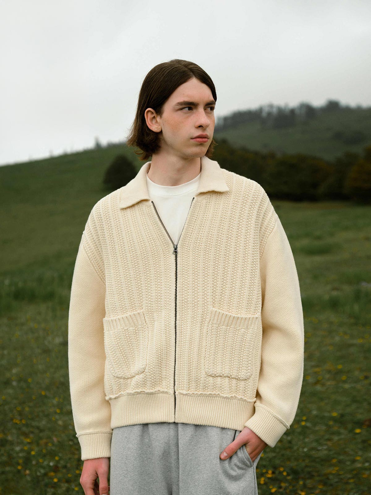 詳細画像: 太い編み目とケーブル模様のディテールを強調した展示。高品質な素材がもたらす柔軟さと安定性をアピール。
モデル画像: モデルが着用したレトロケーブル編みニットカーディガンの全体スタイリング。日常やアウトドアにぴったりなルーズフィットデザインを強調。